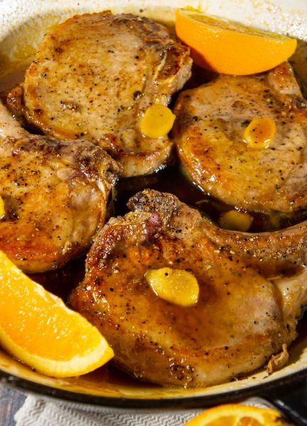 a pan of stove top pork chops in orange ginger sauce