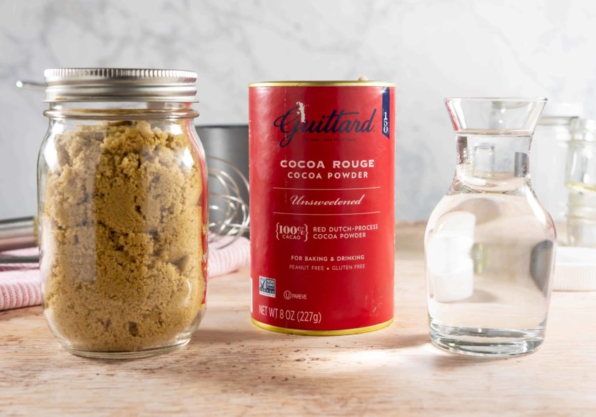 A jar of cocoa powder, brown sugar, and a vial of water