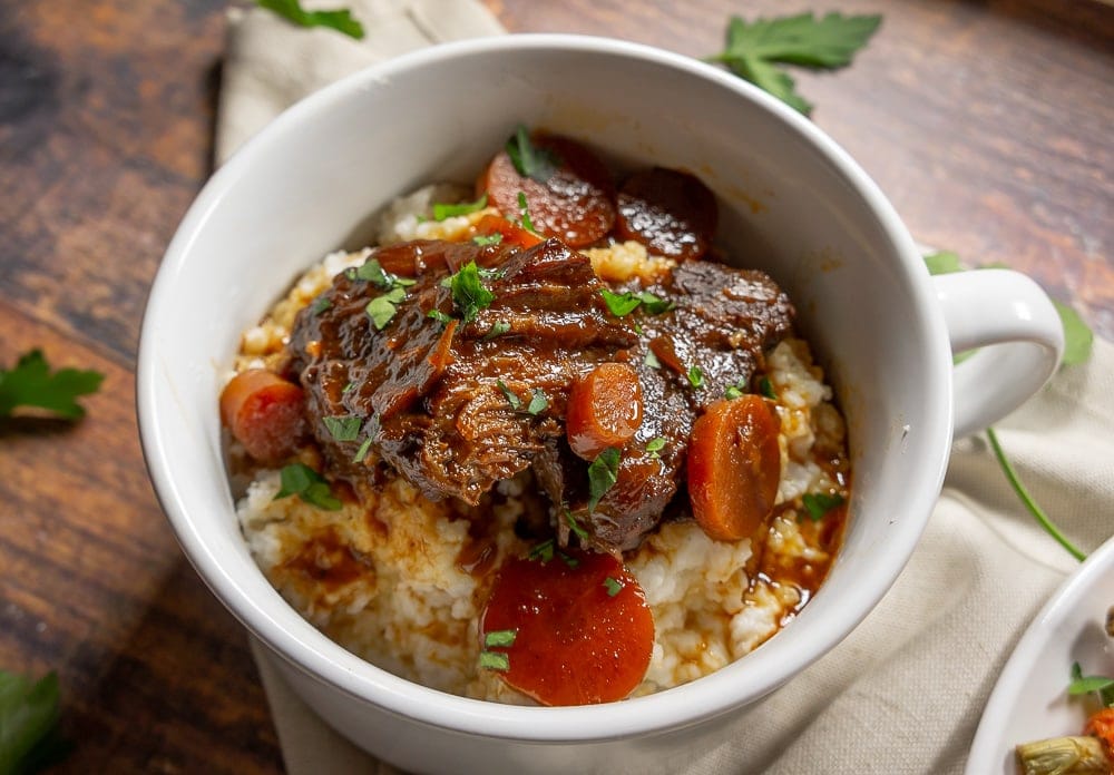 White bowl with braised beef over grits