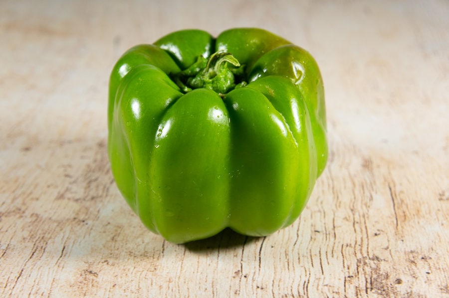 a green bell pepper on a wooden table