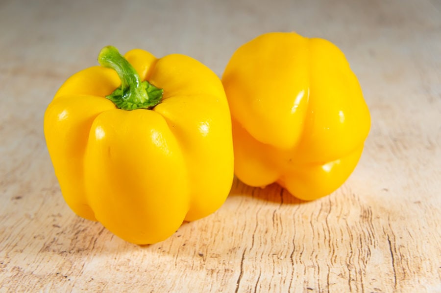 2 yellow bell peppers on a wooden table