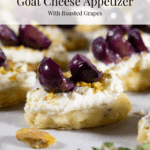 close up of a homemade cracker topped with goat cheese, pistachios, and roasted grapes