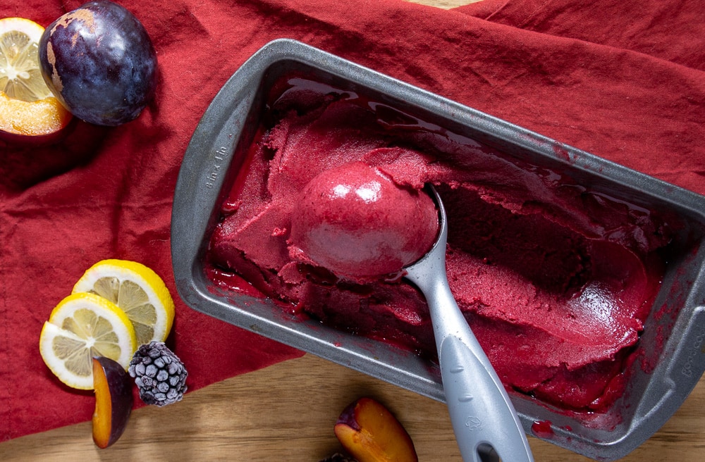 a loaf pan with an ice cream scoop and a scoop of sorbet