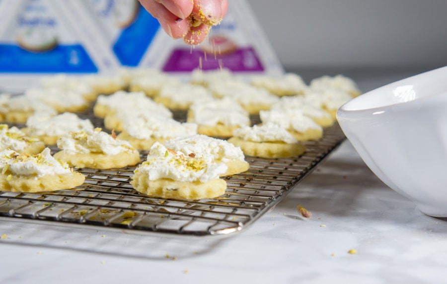 sprinkling pistachios over goat cheese covered crackers