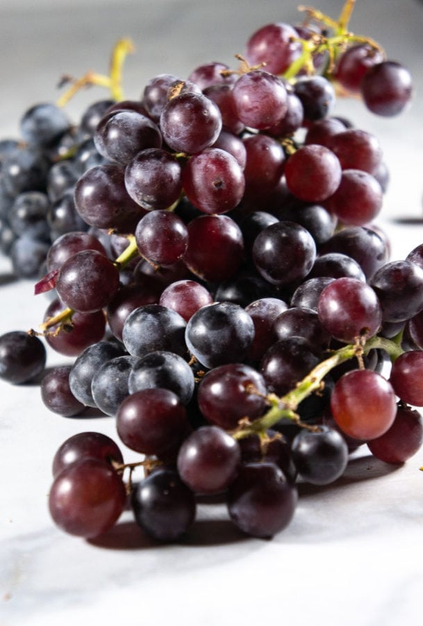 a large cluster of thomcord dark purple grapes