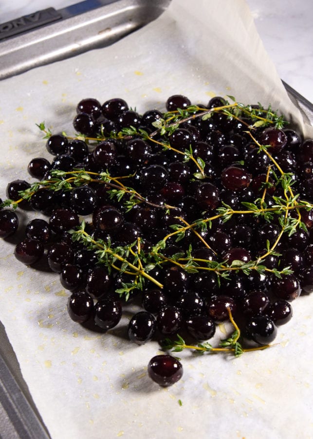 fresh grapes coated in olive oil and salt with fresh thyme on parchment paper