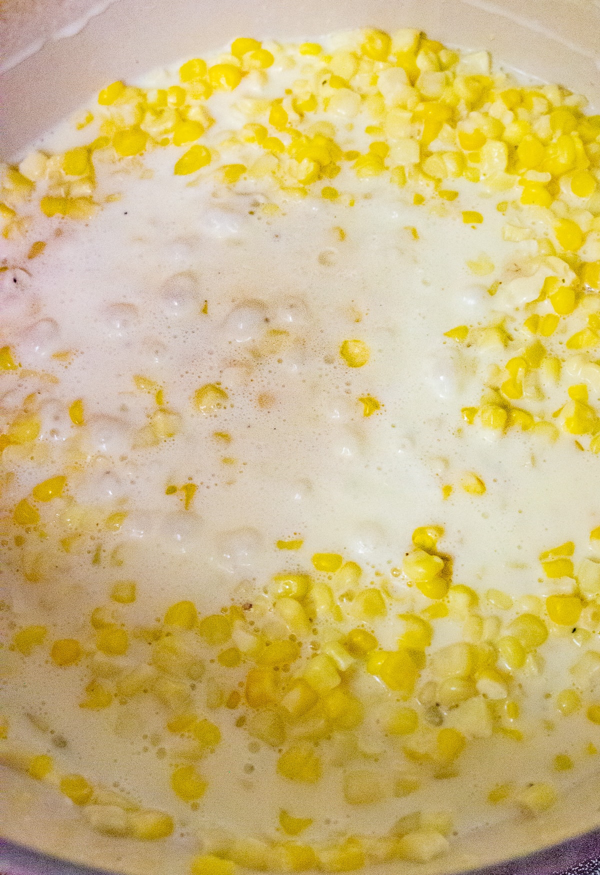 a pot of cream, cheese, and corn kernels cooking .