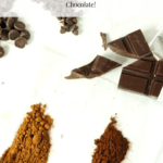 A white table with cocoa powder in lines, a broken chocolate bar, and two piles of chocolate chips