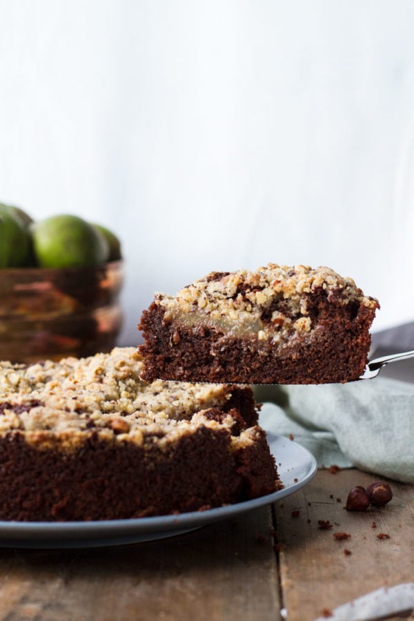 A slice of chocolate pear cake being lifted from the whole cake