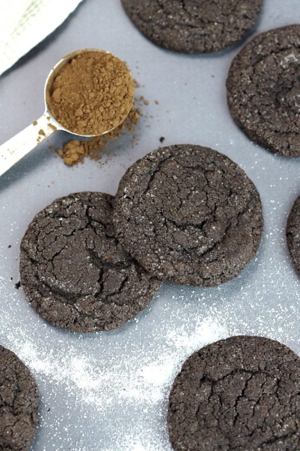 scattered chocolate cookies with a silver spoon of cocoa powder and white sugar scattered around.