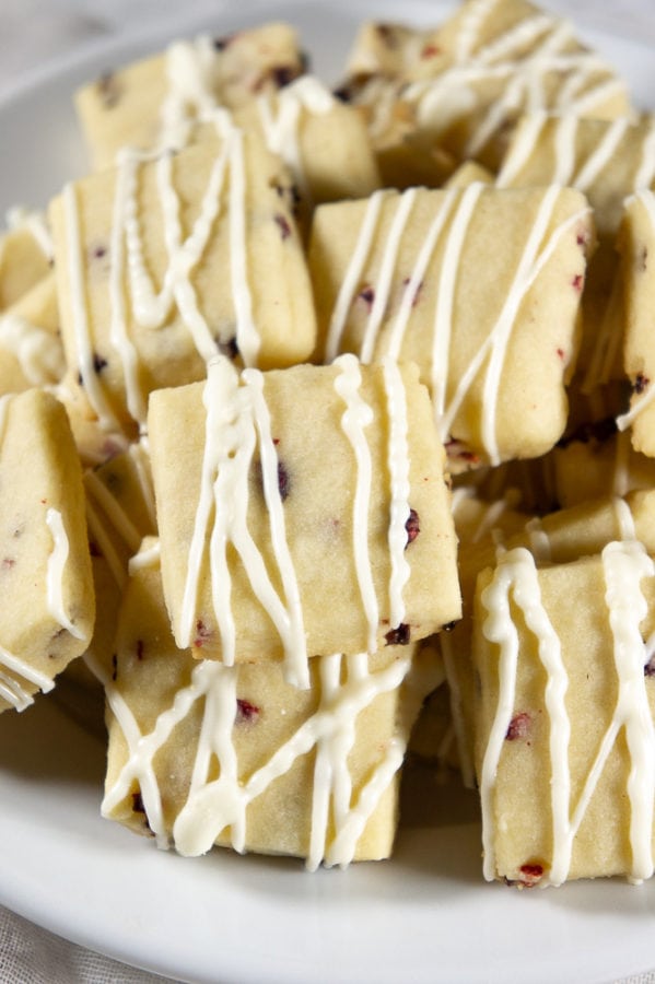 a white bowl of raspberry shortbread cookies drizzled with chocolate