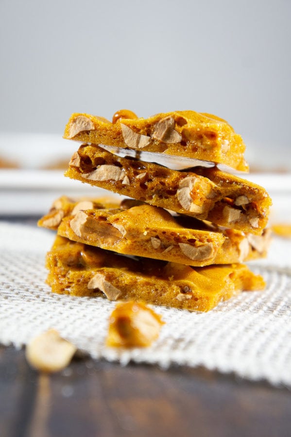 Stacked peanut brittle on a white burlap strip with scattered brittle shards around it