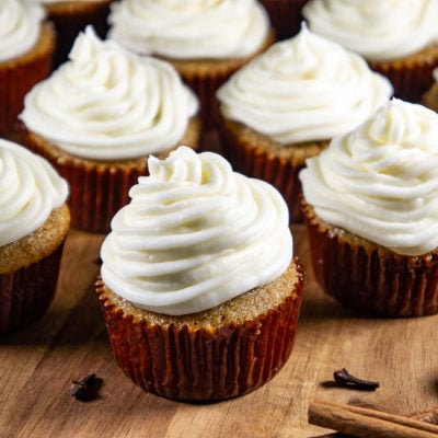 a wooden board of cupcakes with cream cheese frosting