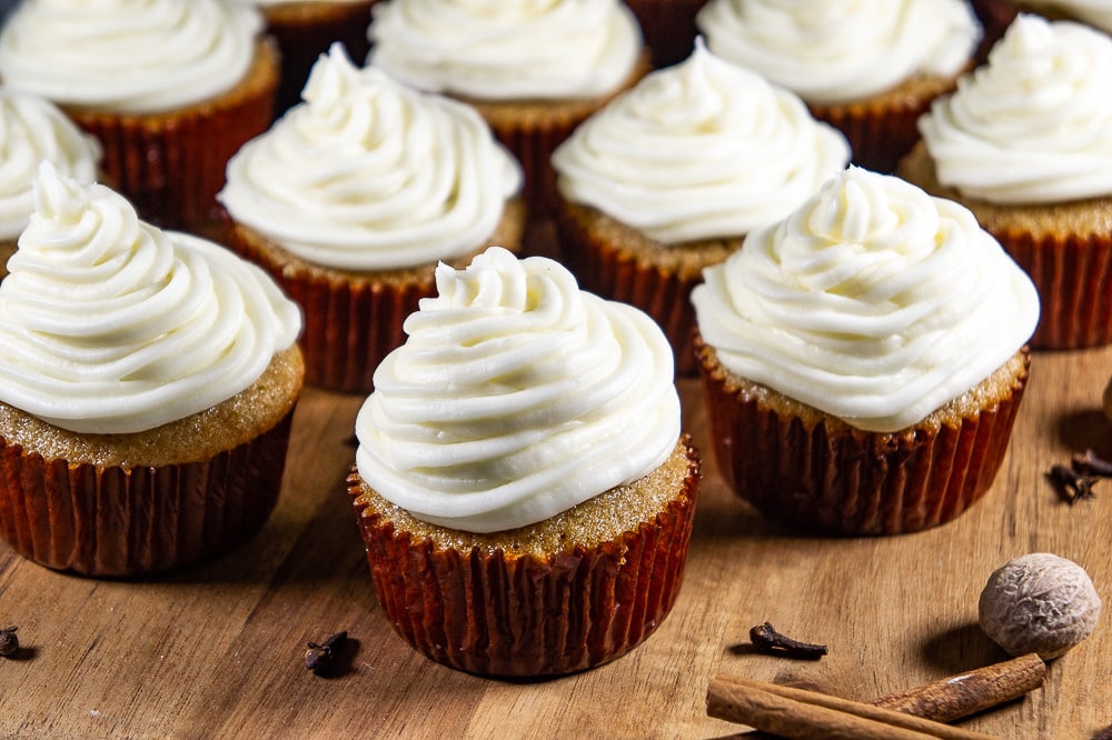 a wooden board of cupcakes with cream cheese frosting