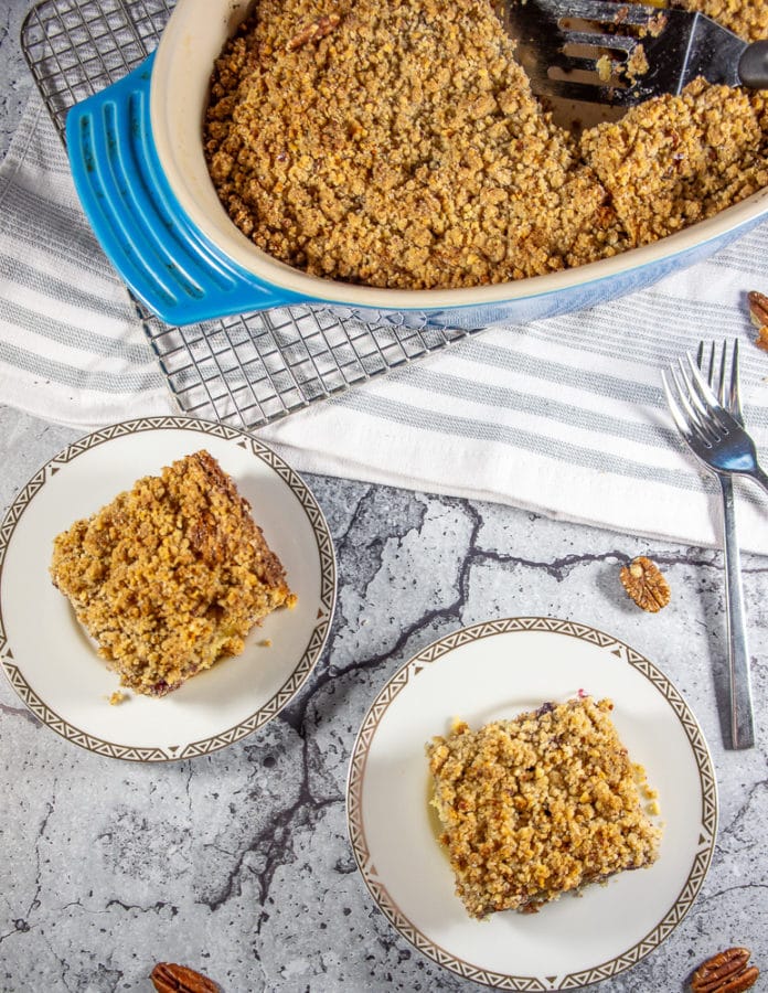A baking dish with coffee cake, beside two small plates with squares of coffee cake on them