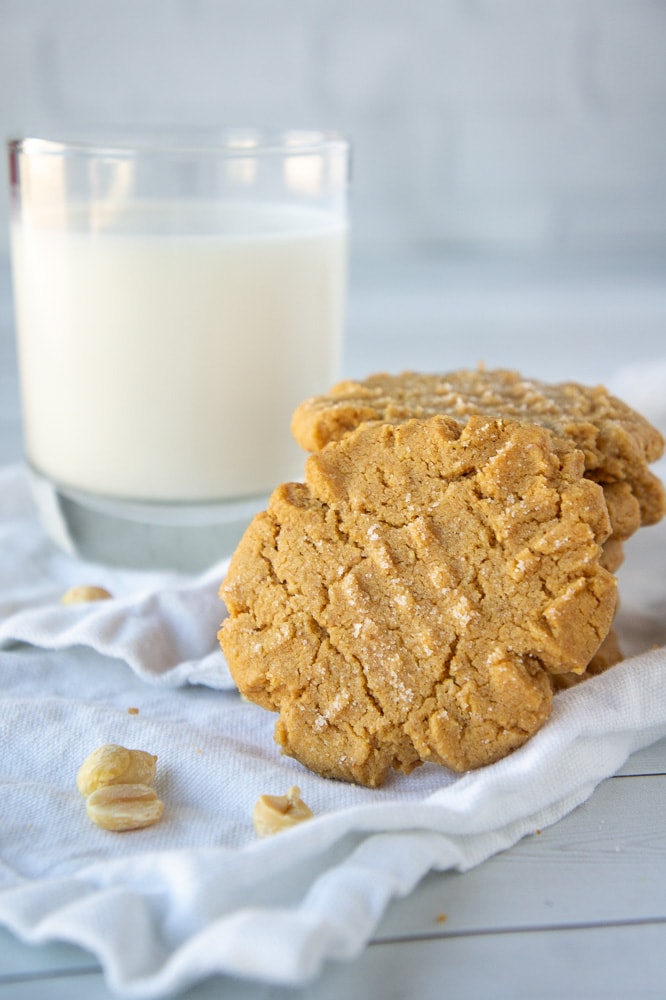 a stack of flourless peanut butter cookies in front of a glass of milk