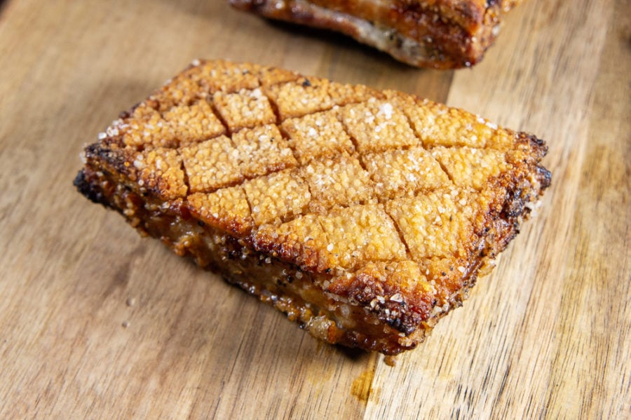 a piece of roasted, salt crust pork belly on a wooden cutting board