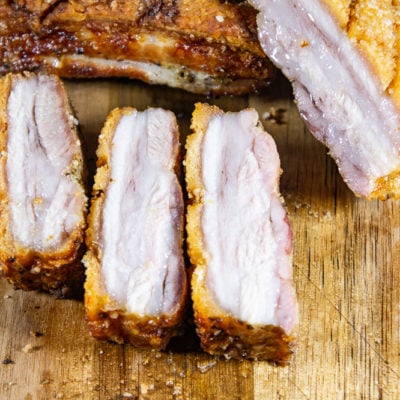 sliced roasted pork belly on a wooden cutting board