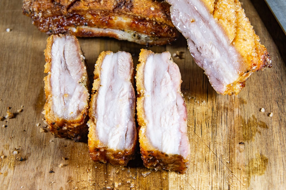 sliced roasted pork belly on a wooden cutting board