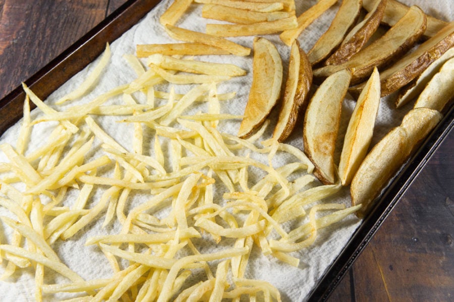 a sheet pan covered in paper towels and lightly blanched french fries 