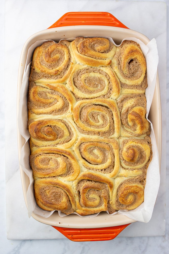 an orange baking dish of golden brown cinnamon rolls