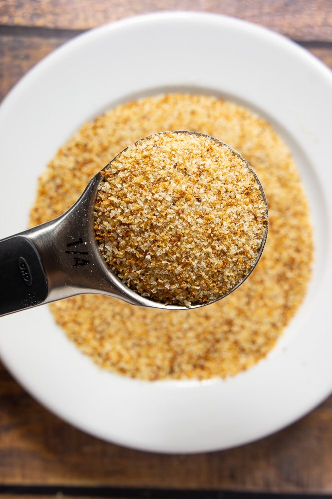 a quarter cup full of breadcrumbs held over a plate of breadcrumbs