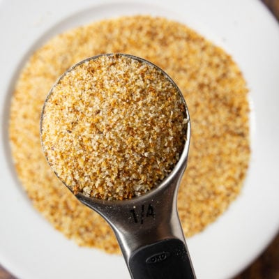 a white plate of breadcrumbs with a quarter cup of them held above it