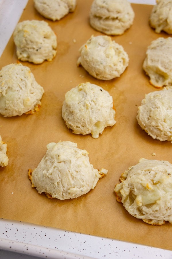 a baking sheet with brown parchment paper and baked drop biscuits