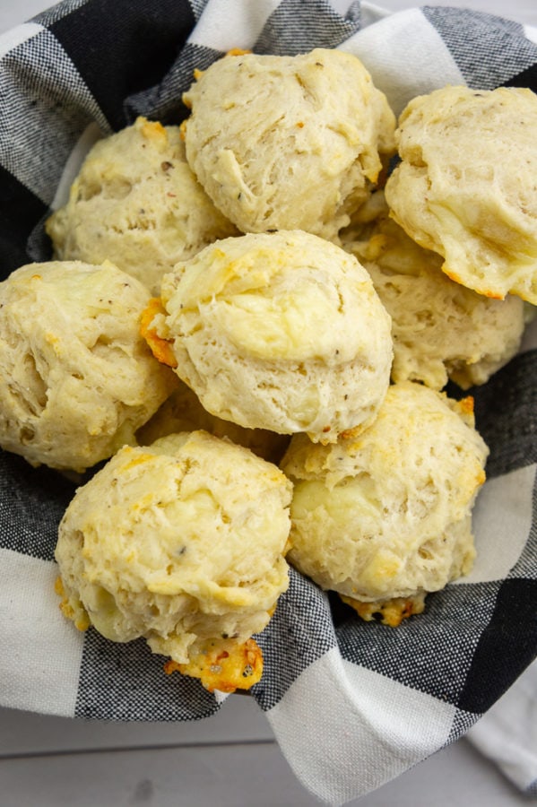 a bowl with a black and white checkered cloth napkin full of biscuits