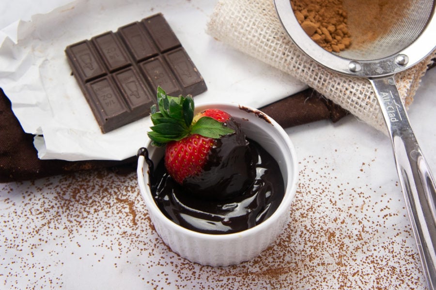 a strawberry in a ramekin full of fudge sauce