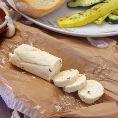 A sliced log of garlic compound butter on parchment paper