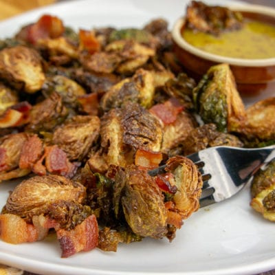 a white platter with fried brussel sprouts and bacon