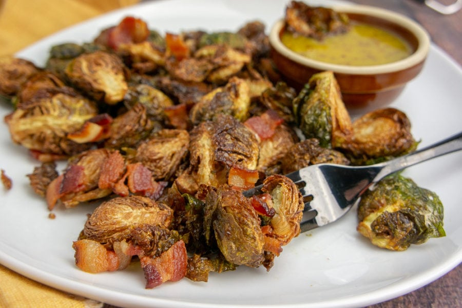 a white platter with fried brussel sprouts and bacon