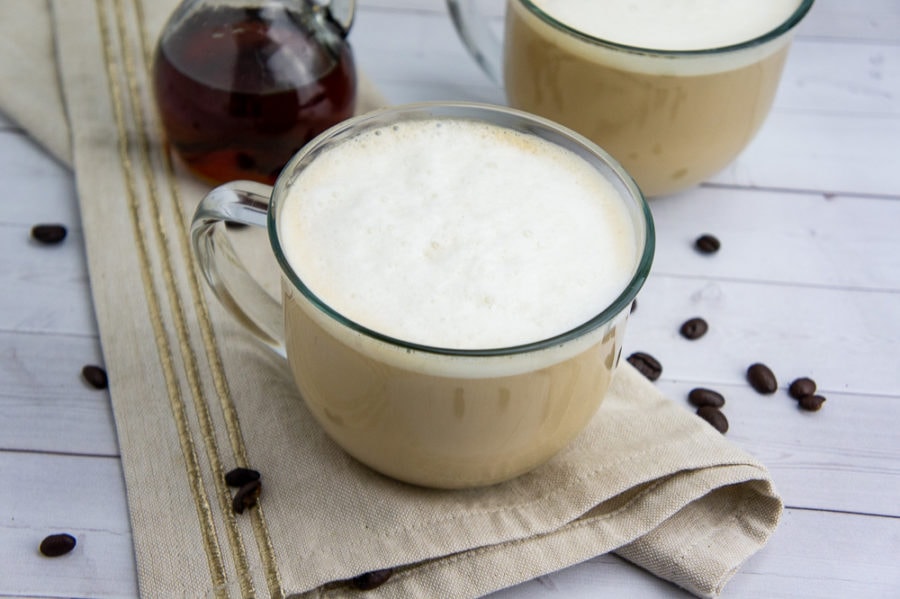 a creamy homemade latte in a glass cup on a beige napkin