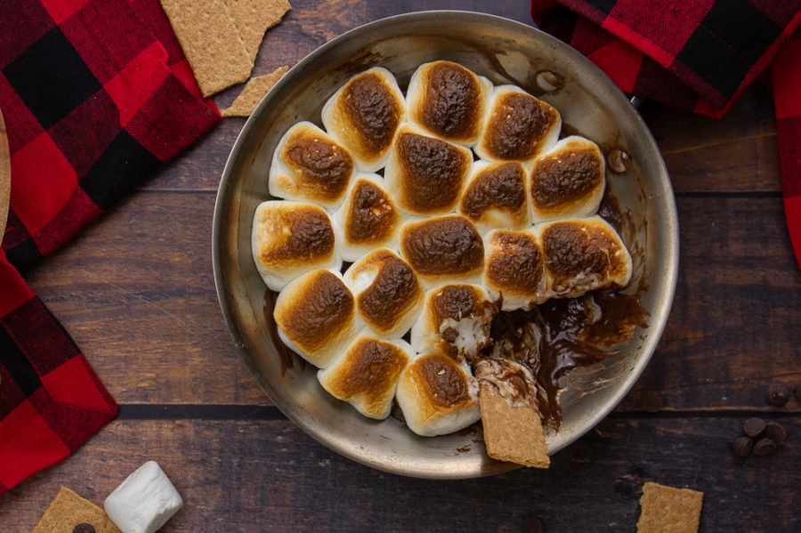 a pan with marshmallow s'mores dip and a graham cracker dipping in