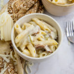 a bowl of mac and cheese with a chunk of white cheese and two forks