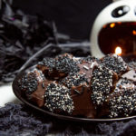 a plate of bat shaped sugar cookies with black and white sprinkle wings
