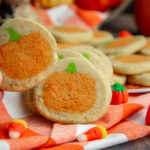 a sugar cookie with a pumpkin in the middle being lifted to reveal an identical one behind it
