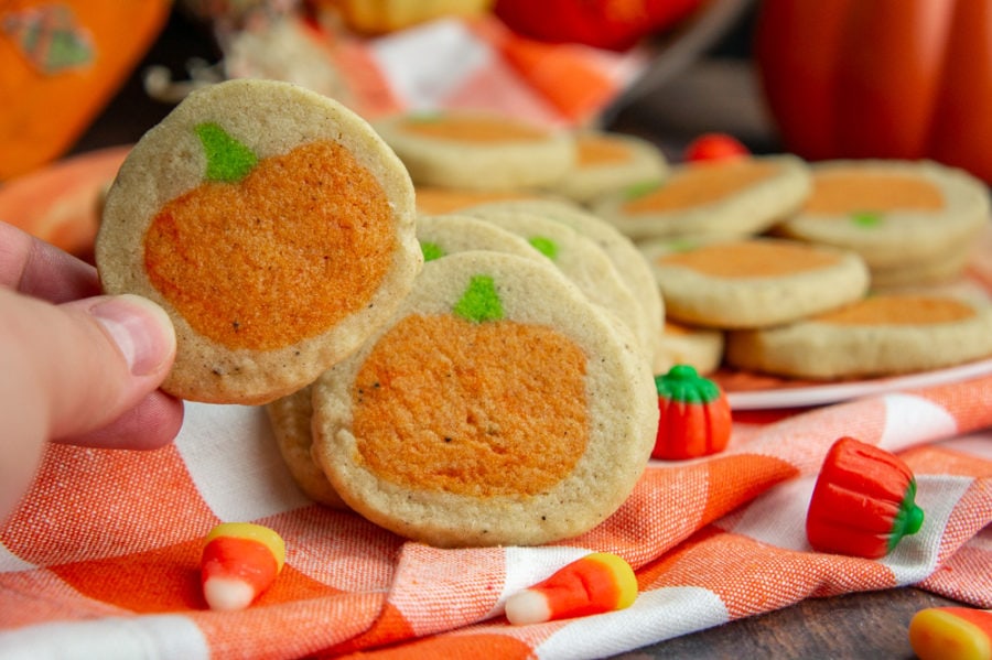a sugar cookie with a pumpkin in the middle being lifted to reveal an identical one behind it