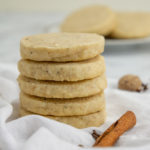 a stack of spiced shortbread cookies next to a cinnamon stick