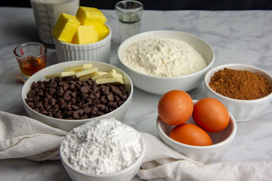 A bowl of powdered sugar, eggs, cocoa, powder, chocolate pieces, and butter