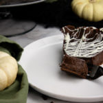 A slice of chocolate tart on a white plate with a fork cutting off a slice