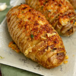 three hasselback potato gratin on a green plate with fresh thyme