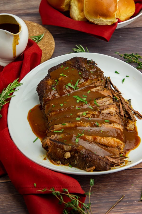 a platter of sliced beef brisket with a red wine sauce poured over top