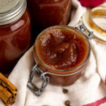 an open jar of apple butter on a white towel with a red stripe