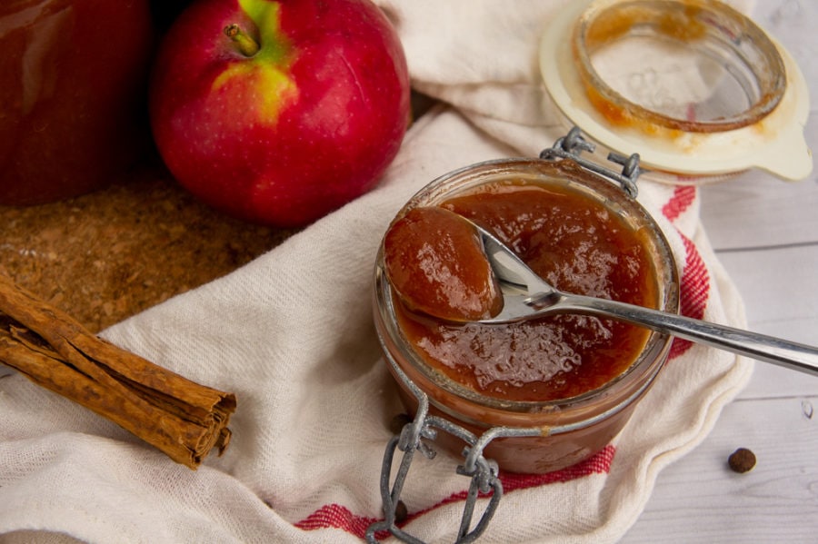 a small jar of apple butter with a spoon scooping some out