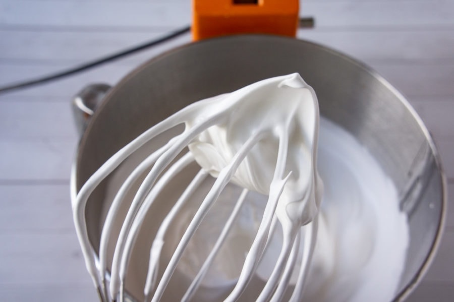 italian meringue on a whisk over a stand mixer bowl