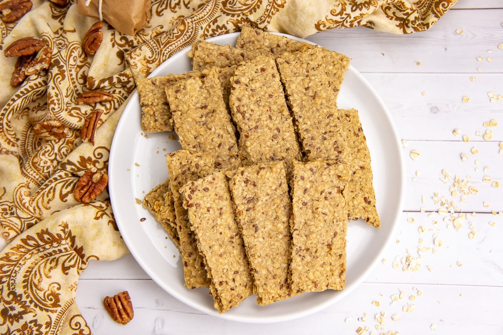 a plate of homemade granola nut bars on a white table with a printed yellow cloth