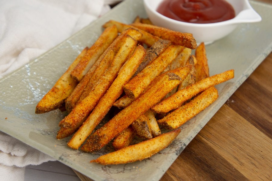 a plate of fried cajun fries with ketchup