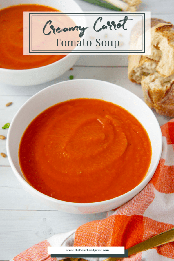 a bowl of tomato carrot soup next to an orange checked towel